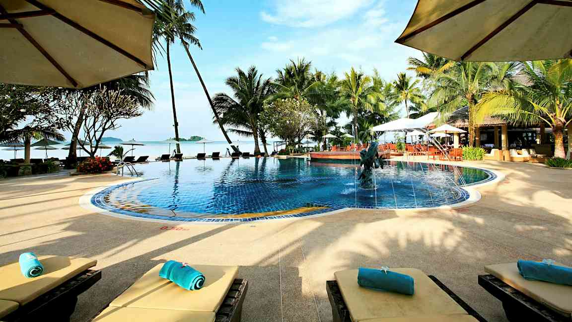 Uima-allas, jota ympäröivät palmut ja aurinkotuolit, näkymä merelle ja sininen taivas. (Tekoälyn luoma teksti)