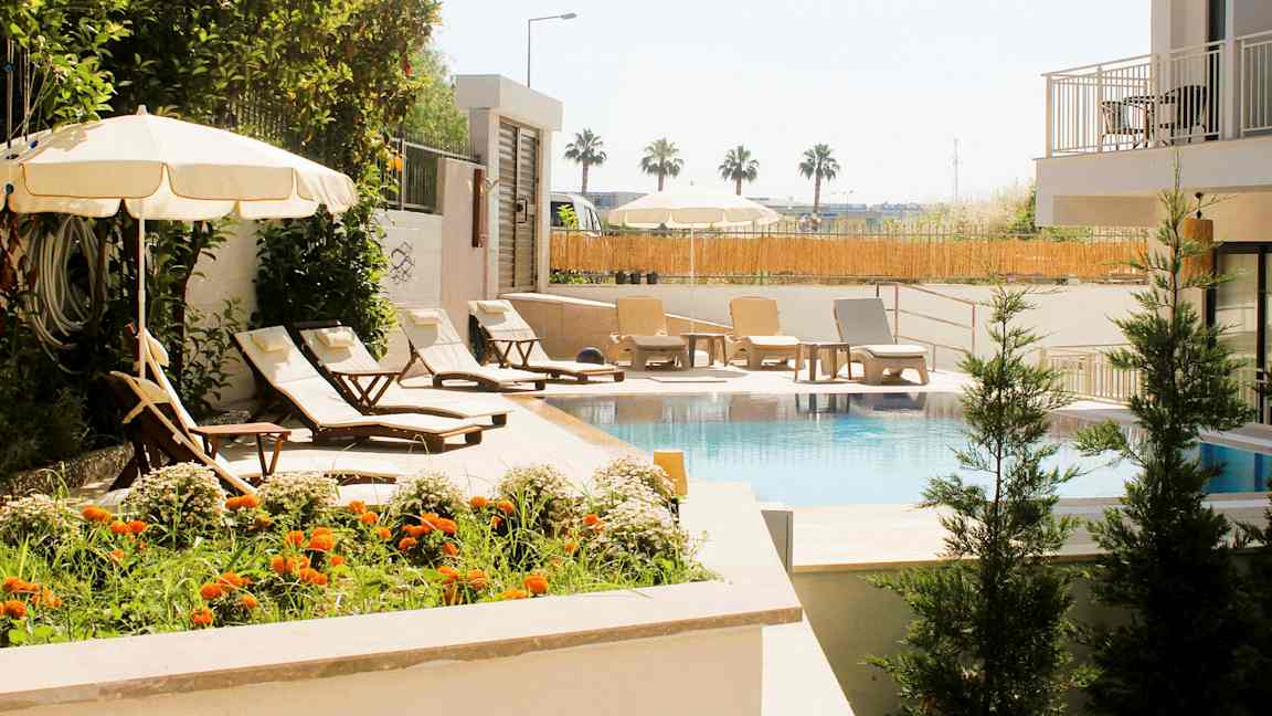 Uima-allas, jonka ympärillä on aurinkotuoleja, varjoja ja vihreää kasvillisuutta. (Tekoälyn luoma teksti)