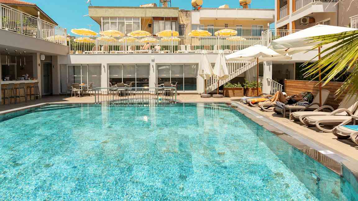 Ulkouima-allas, jota ympäröivät aurinkotuolit ja aurinkovarjot hotellilla. (Tekoälyn luoma teksti)
