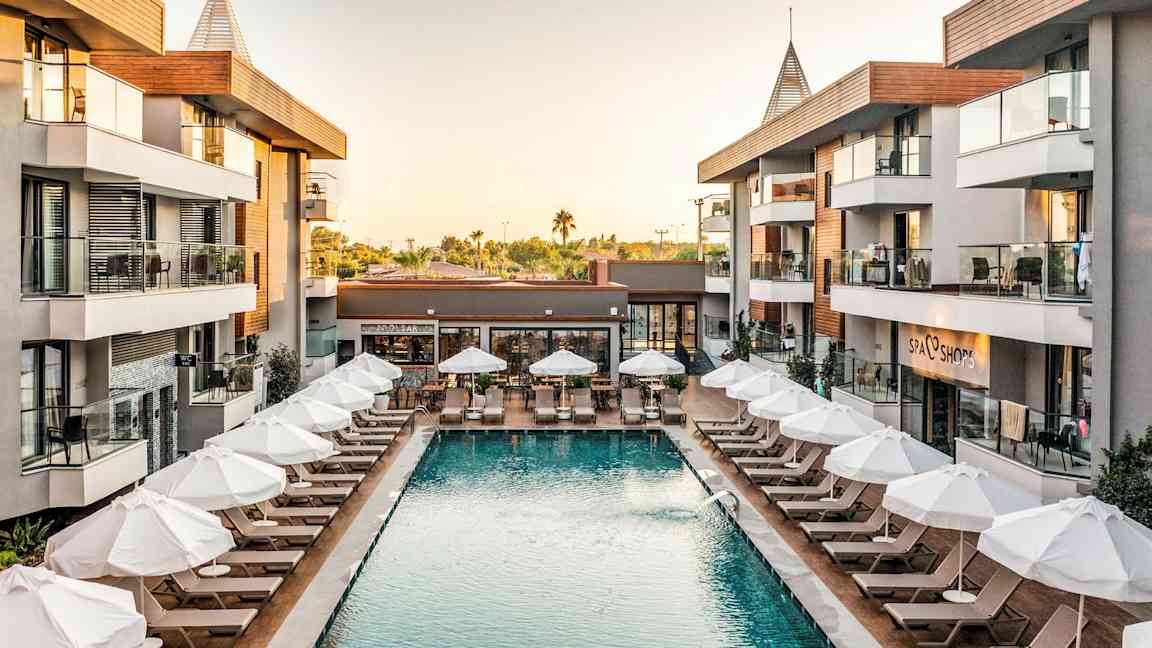 Hotellialue, jossa uima-allas ja aurinkotuoleja rakennusten ympäröimänä. (Tekoälyn luoma teksti)