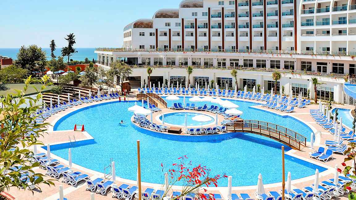 Hotelli suurella uima-altaalla ja aurinkotuoleilla lähellä merta. (Tekoälyn luoma teksti)