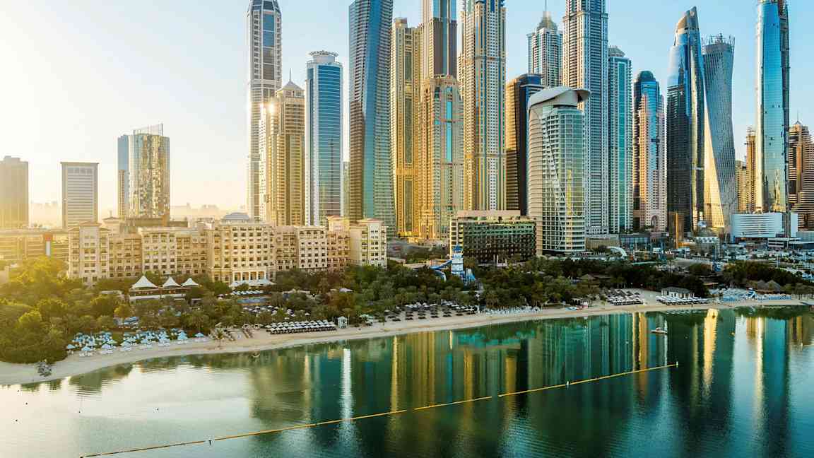 Kaupunkinäkymä, jossa korkeita rakennuksia ja ranta veden äärellä etualalla. (Tekoälyn luoma teksti)