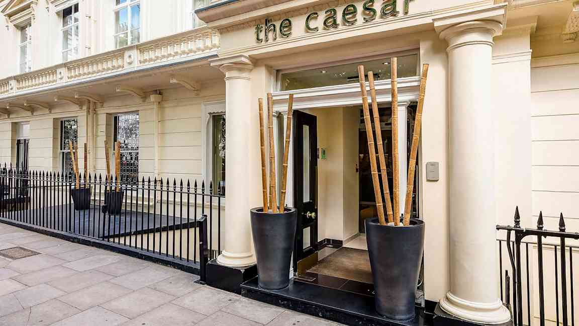 Hotelli The Caesarin sisäänkäynti, jota ympäröi musta rautaportti. (Tekoälyn luoma teksti)
