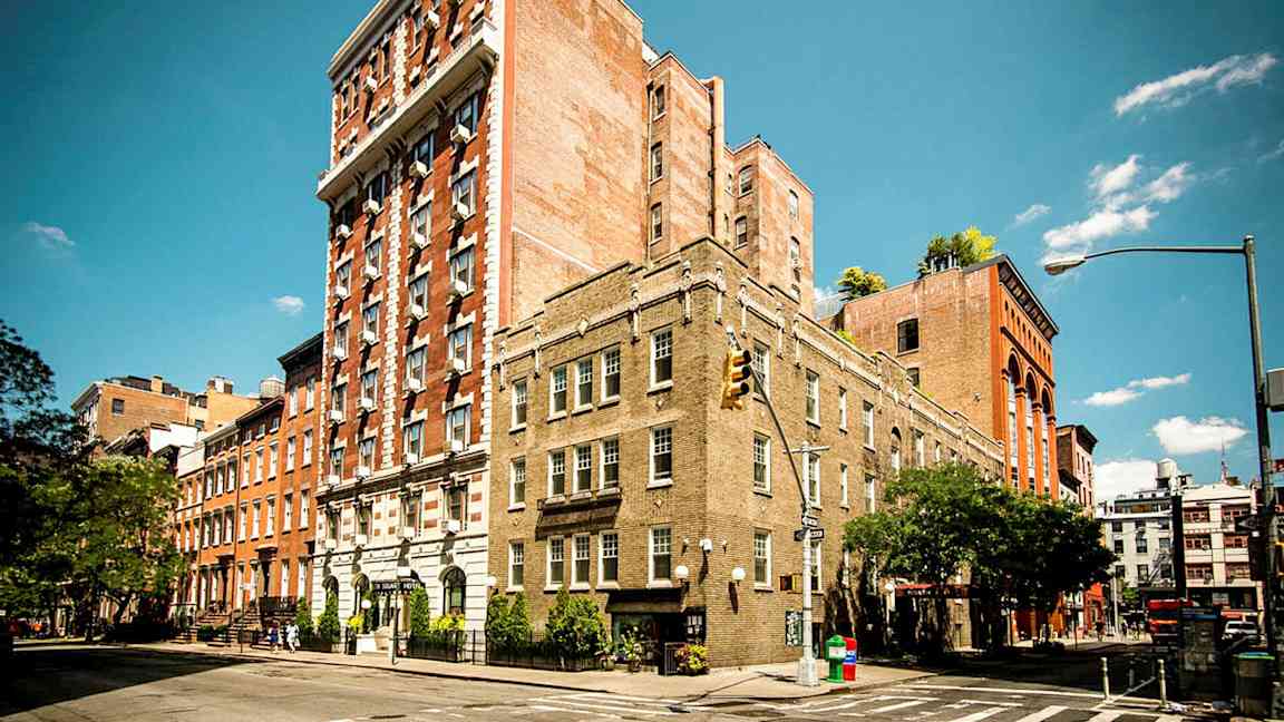 Useita tiilirakennuksia kadunkulmassa kirkkaan sinisen taivaan alla. (Tekoälyn luoma teksti)