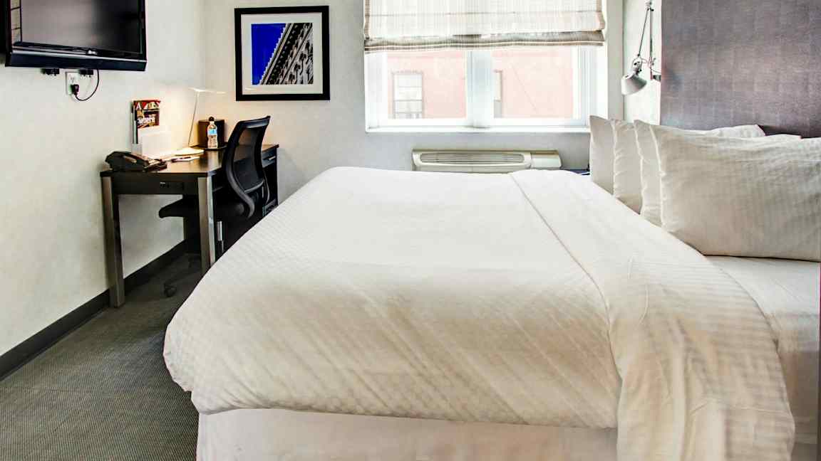 Makuuhuone, jossa on parivuode, työpöytä, tuoli ja seinälle kiinnitetty televisio. (Tekoälyn luoma teksti)