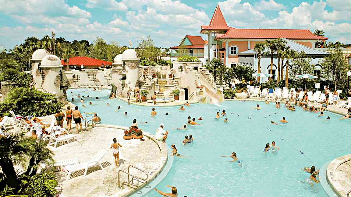 Ulkouima-allas, jota ympäröivät ihmiset, aurinkotuolit ja rakennukset. (Tekoälyn luoma teksti)