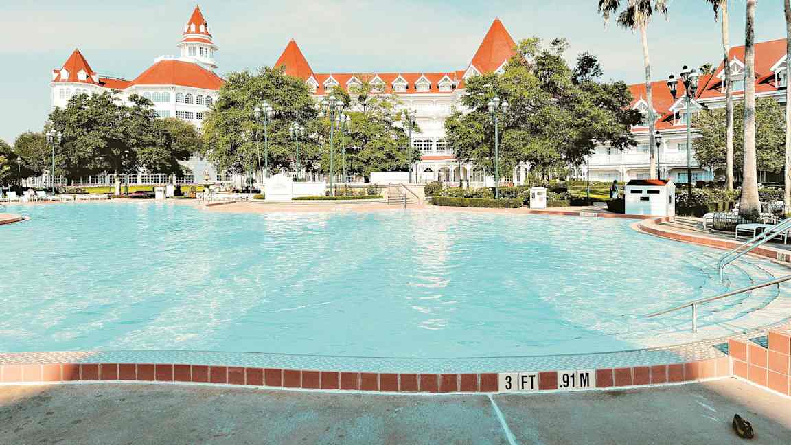 Kuva uima-altaasta, jonka taustalla on tyylikäs valkoinen hotelli ja punaiset katot. (Tekoälyn luoma teksti)