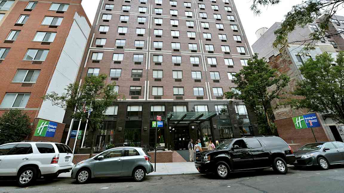 Kerrostalo, jossa lasiovi ja parkkeerattuja autoja edessä. (Tekoälyn luoma teksti)