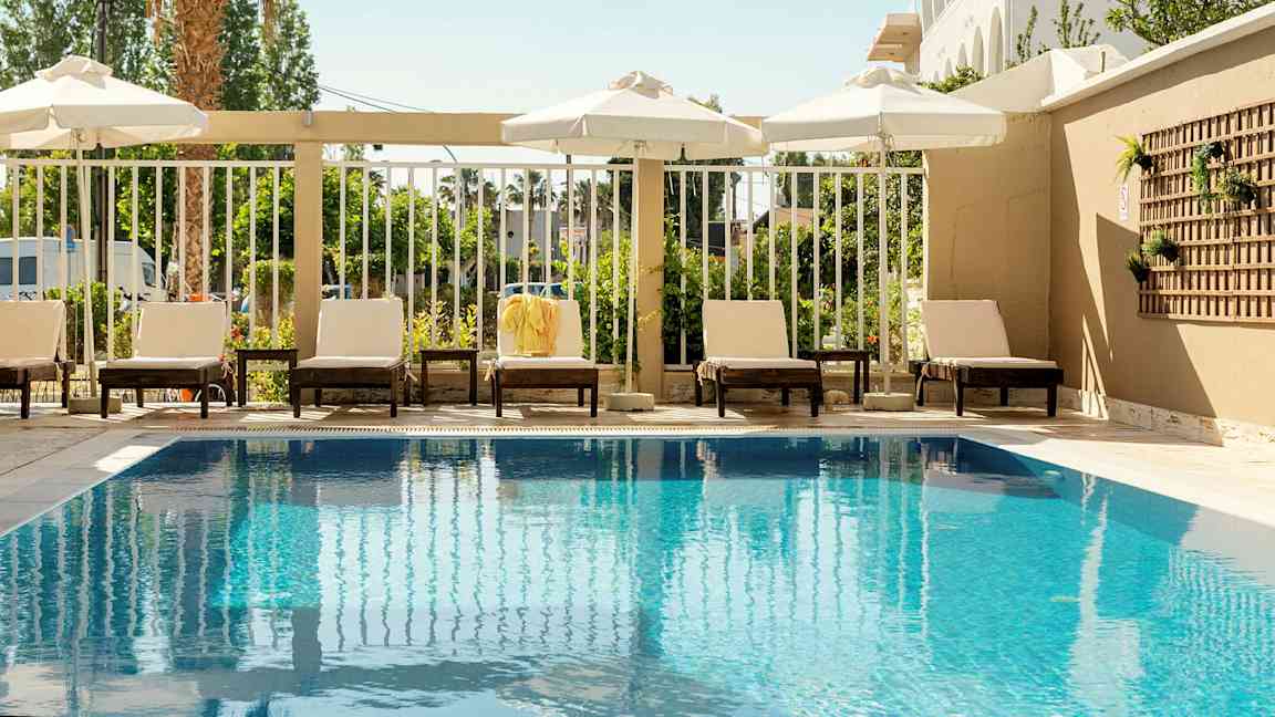 Ulkoallas, jonka reunalla aurinkotuoleja ja aurinkovarjoja. (Tekoälyn luoma teksti)