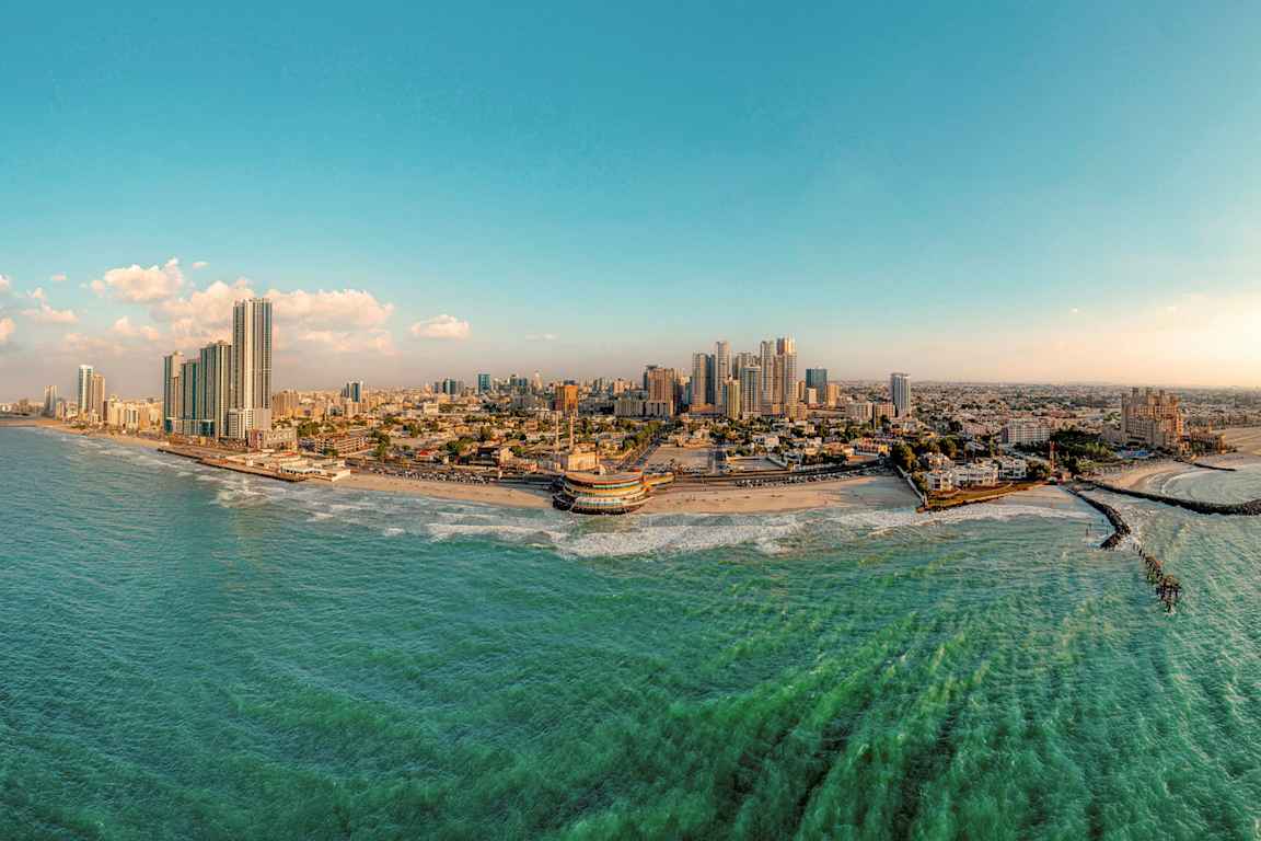 Panoraamakuva rannikkokaupungista, jossa on korkeita rakennuksia, ranta ja meri. (Tekoälyn luoma teksti)