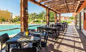 Ulkoterassi, jossa pöytiä ja tuoleja uima-altaan vieressä. (Tekoälyn luoma teksti)