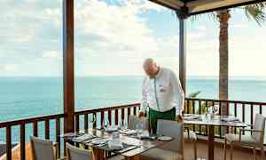 Ruokailutila, jossa katetut pöydät terassilla merinäköalalla. (Tekoälyn luoma teksti)