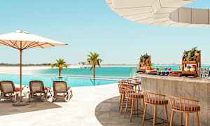 Uima-allas rannalla, jossa on aurinkotuoleja, varjo ja allasbaari eksoottisine hedelmineen. (Tekoälyn luoma teksti)