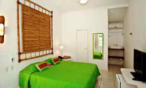 Vaalea makuuhuone, jossa on vihreä sänky, seinällä peili ja bambukoriste. (Tekoälyn luoma teksti)