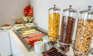 Aamiaisbuffet, jossa on kulhoja viljatuotteita, kananmunia, hedelmiä ja leikkeleitä. (Tekoälyn luoma teksti)