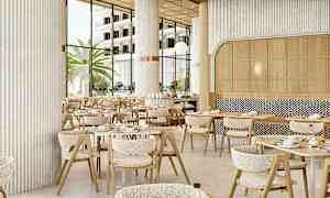 Ravintolaympäristö, jossa on nykyaikaisia pöytiä ja tuoleja, suuret ikkunat päästävät luonnonvaloa sisään, ja ulkona näkyy palmuja. (Tekoälyn luoma teksti)