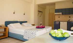 Huoneessa on sänky, jossa on sininen sängynpääty, keittiö ja pöytä hedelmillä. (Tekoälyn luoma teksti)