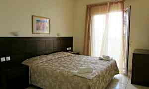 Hotellihuone, jossa on parivuode, yöpöytä ja avoin parvekkeen ovi. (Tekoälyn luoma teksti)