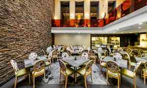 Ravintolan sisustus, jossa on tuoleja ja pöytiä sekä kiviseinä. (Tekoälyn luoma teksti)