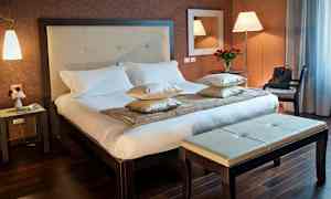 Hotellihuone, jossa on parivuode, yöpöytä ja penkki. (Tekoälyn luoma teksti)