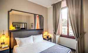 Hotellihuone, jossa parivuode, yöpöytä, peili ja ikkuna beigeillä verhoilla. (Tekoälyn luoma teksti)