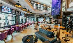 Kutsuva baari, jossa on modernit huonekalut ja koristeellisia elementtejä, kuten taideteoksia ja veistoksia. (Tekoälyn luoma teksti)