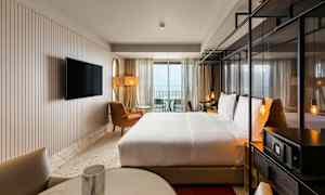 Hotellihuone, jossa parivuode, istuimet ja TV sekä parveke näkymillä. (Tekoälyn luoma teksti)