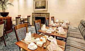 Miellyttävästi katettu huone, jossa on puutuoleja ja katettuja pöytiä. (Tekoälyn luoma teksti)