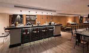 Moderni baari, jossa on korkeita tuoleja baaritiskin ympärillä ja tyylikäs sisustus. (Tekoälyn luoma teksti)