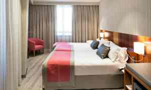 Hotellihuone, jossa kaksi erillistä vuodetta, yksinkertaiset modernit kalusteet ja ikkuna taustalla. (Tekoälyn luoma teksti)