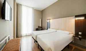 Kahden hengen huone, jossa on kaksi erillistä vuodetta, televisio ja nojatuoli. (Tekoälyn luoma teksti)