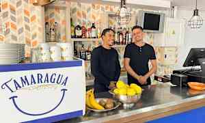 Baari, jonka tiskissä on teksti "Tamaragua". Tiskillä on hedelmiä ja astioita. Taustalla on hyllyjä, joissa on pulloja. (Tekoälyn luoma teksti)