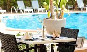 Pöytäkattaus uima-altaan vieressä, ympärillä aurinkotuoleja. (Tekoälyn luoma teksti)