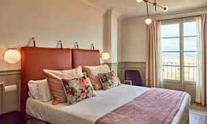 Hotellihuone, jossa on sänky, koristeellisia tyynyjä ja ikkuna näkymällä. (Tekoälyn luoma teksti)