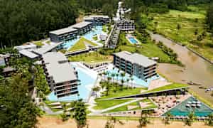 Ilmakuva hotellialueesta, jossa on uima-altaita ja ympäröivää vihreyttä. (Tekoälyn luoma teksti)