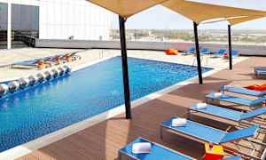 Moderni uima-allas, jossa on sinistä vettä, ympäröity aurinkotuoleilla ja varjokatteilla. (Tekoälyn luoma teksti)