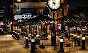 Ravintolan tai hotellin ulkoterassi, jossa on kilpi ja kello, yövalaistus. (Tekoälyn luoma teksti)