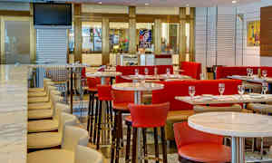 Moderni ravintolansisustus, jossa on pöytiä, tuoleja ja baari korkeilla tuoleilla. (Tekoälyn luoma teksti)