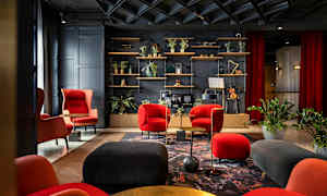 Tyylikäs lounge, jossa on punaisia ja mustia huonekaluja, kasveja ja koriste-esineitä hyllyllä. (Tekoälyn luoma teksti)