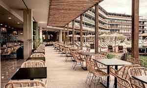 Ulkoterassi rottinkikalusteilla, näkymä uima-altaalle ja aurinkotuoleihin. (Tekoälyn luoma teksti)