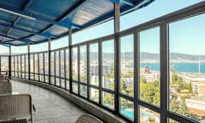 Sisätila, jossa on lasitettu veranta ja näkymä kaupungin ja meren yli. (Tekoälyn luoma teksti)