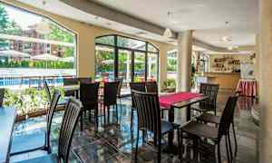 Ravintola, jossa pöytiä ja tuoleja, suuret ikkunat avautuvat ulkoalueelle. (Tekoälyn luoma teksti)