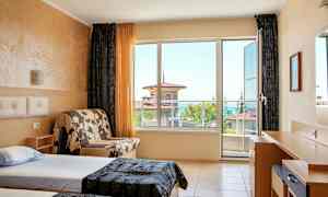 Hotellihuone, jossa on kaksi erillistä vuodetta, sohva ja kirjoituspöytä, suuret ikkunat ja näkymä merelle. (Tekoälyn luoma teksti)