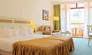 Hotellihuone, jossa on parivuode, istuinryhmä nojatuoleineen ja pöytineen sekä parveke kalusteineen ja näkymineen. (Tekoälyn luoma teksti)