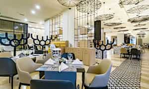 Moderni ravintola, jossa on tyylikkäät kalusteet ja hienostunut katto. (Tekoälyn luoma teksti)