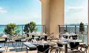 Terassi, jossa katetut pöydät ja näkymä merelle. (Tekoälyn luoma teksti)