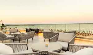 Näkymä kalustetulta terassilta, jossa istuinpaikkoja ja meri taustalla. (Tekoälyn luoma teksti)