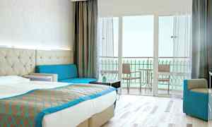 Hotellihuone, jossa on parivuode, sohva ja parveke merinäköalalla. (Tekoälyn luoma teksti)