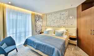 Hotellihuone, jossa on parivuode, sininen päiväpeite ja koristeellinen seinä sängyn takana. (Tekoälyn luoma teksti)