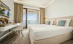 Hotellihuone, jossa kaksi sänkyä, kirjoituspöytä ja parveke merinäköalalla. (Tekoälyn luoma teksti)